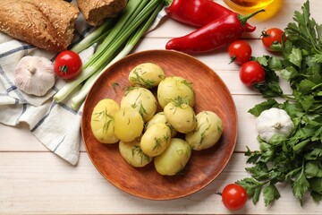Tasty young boiled potatoes with dill and other products on wooden table, flat lay