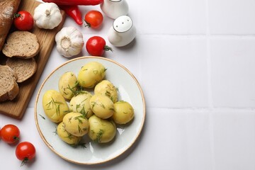 Tasty young boiled potatoes with dill and products on white tiled table, flat lay. Space for text