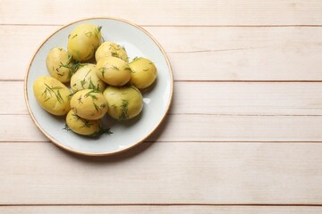 Tasty young boiled potatoes with dill on wooden table, top view. Space for text