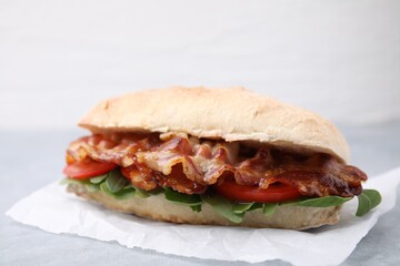 Tasty sandwich with bacon on grey table, closeup