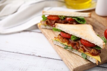 Delicious sandwiches with fried bacon on wooden rustic table, closeup. Space for text