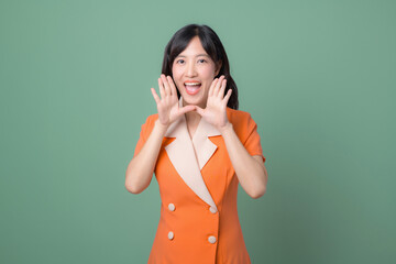 Smiling Asian Woman in Orange Dress Speaking Gesturing with Hand on Green Background