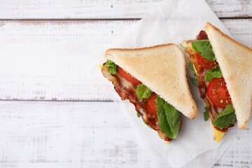 Delicious sandwiches with fried bacon on wooden rustic table, top view. Space for text