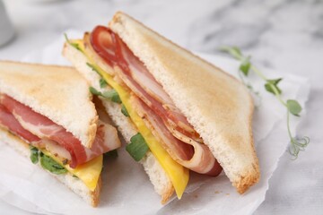 Delicious sandwiches with bacon on white table, closeup