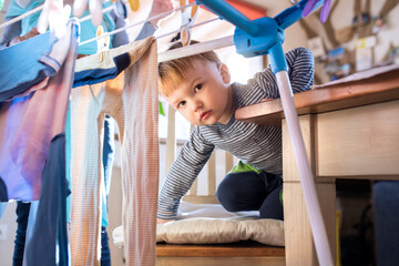 Young son helping mother with hosehold chores, hanging clothes on drying rack. Weekly chores,...
