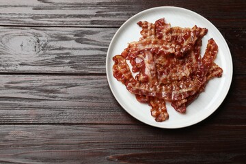 Slices of tasty fried bacon on wooden table, top view. Space for text
