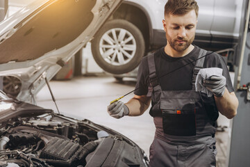 Car mechanic checking the engine oil level in the service center