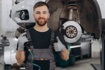 Technician work car service. Auto mechanic portrait. Guy fix big wheel tire workshop. Happy worker...