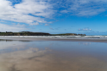 Reflets du ciel bleu et des nuages sur le sable mouillé d'une plage de la presqu'île de Crozon.