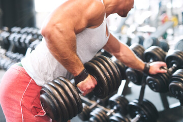 Close up of man performing single arm dumbbell row in bent-over position. Routine workout for physical and mental health.