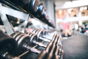 Rows of metal dumbbells on rack for strength training in gym.