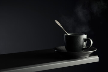 Black cup of coffee on a black background.
