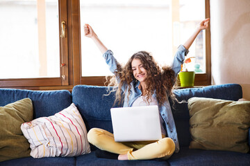 A beautiful student reading admission letter from university, sitting at home on the couch. Hands...