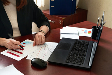 Rear view of female financial manager drawing various charts and schemes on wall in office