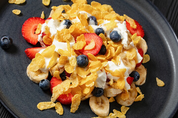 fresh berries, banana with corn flakes and yogurt