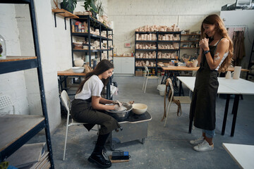 Woman potter making with pottery wheel in cozy workshop having master class