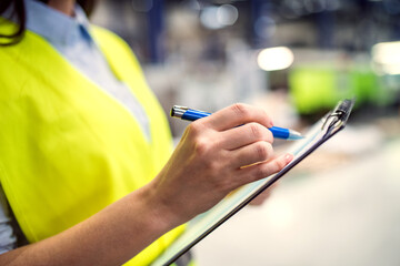 Manager woman in business casual clothes controlling goods in warehouse.