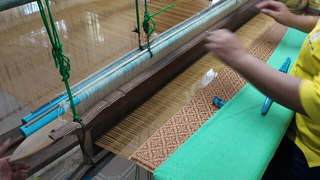 Thai Woman Making Ties Mudmee Board Weaving or Ikat Thai Silk Pattern Weaving on Small Red Weaving Mill Before Bring to Tie and Dyed in Thailand