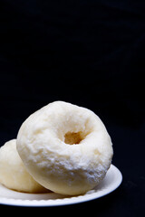 Donut with icing sugar placed on white plate. Close-up donut texture with black background. Dessert for snack time with the concept of sweet taste and still life food. Delicious donuts with copy space