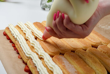 Cover the rows of savoiardi cookies with whipped cream and mascarpone cheese.