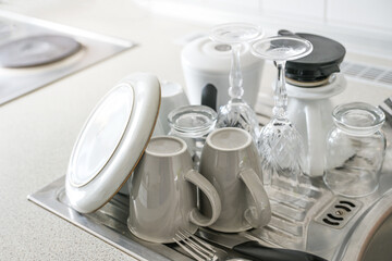Washed dishes set out to dry next to the sink in the kitchen in a minimalist household without a...