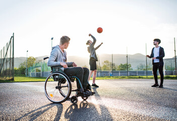Obraz premium Disabled young man feeling excluded, want to play basketball with his friends, but because of wheelchair he can't.