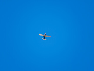 Small ultralight airplane with overhead wing and single propeller flying in sunset sky.