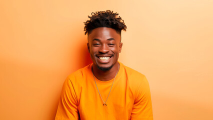Fototapeta premium Portrait of a young man in casual clothing smiling against an orange background. Bright and cheerful imagery showcasing happiness and modern style.