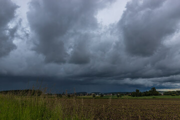 Landschaftsaufnahme von einer Gewitterwolkenformation, über Felder und Wiesen.