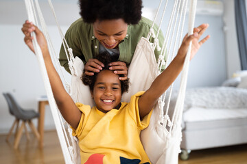 Loving mother playing with her young girl at home.