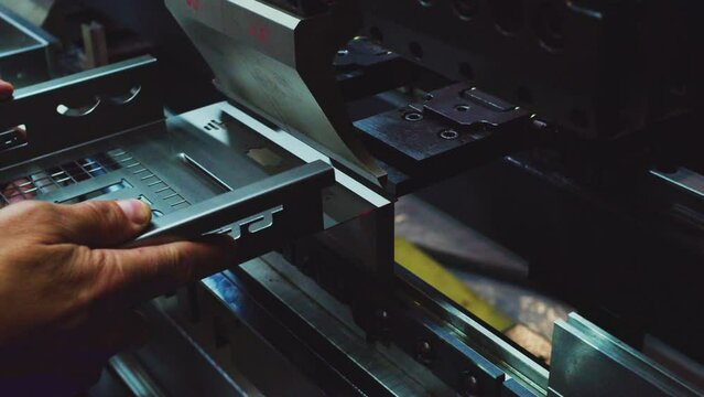 Worker hands bend metal sheet on a modern bending industrial machine at a factory. Close-up