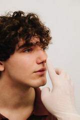 Fototapeta premium ENT doctor touching nose of patient before rhinoplasty or septoplasty surgery. Rhinoplasty to change size or shape of nose and fix issues from injury or improve breathing problems.