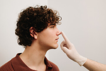 Rhinoplasty to change size or shape of nose and fix issues from injury or improve breathing problems. ENT doctor touching nose of patient before rhinoplasty or septoplasty surgery.
