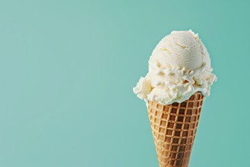 Vanilla ice cream scoop on cone against turquoise backdrop