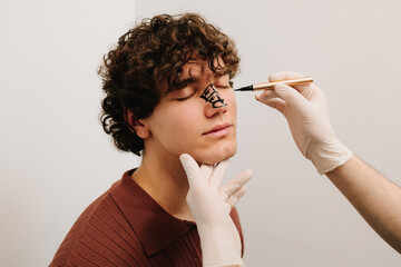 Obraz premium Surgeon drawing markup on nose before rhinoplasty surgery. Preparation for septoplasty and rhinoplasty. Cosmetic surgery procedure to reshapes nose.