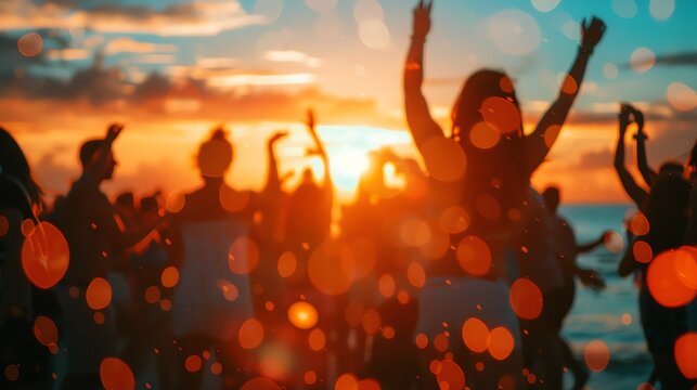 Silhouettes of people dancing at a beach party during sunset.