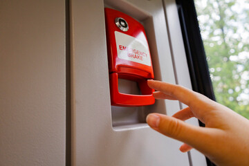 A person is using their finger to press a red button on a wall