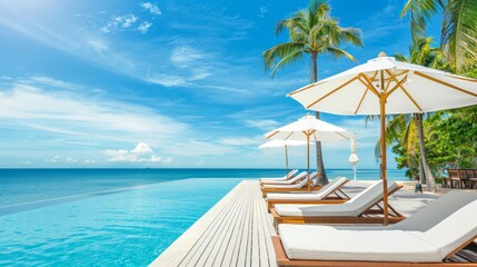 Obraz premium Luxurious beach resort with pool, beach chairs, umbrellas, palm trees, blue sky, and sea horizon