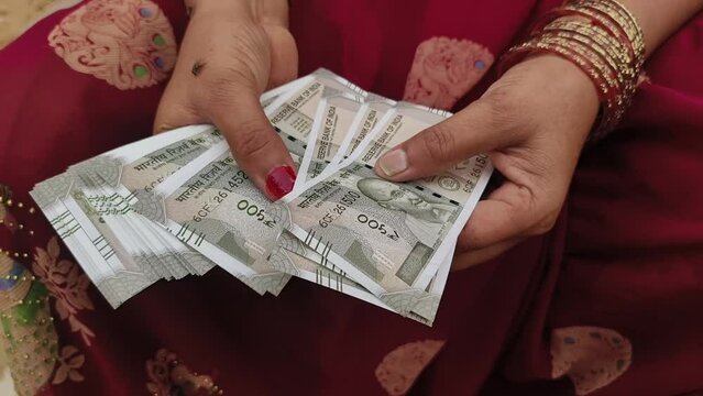 An Indian female counting 500 rupees Indian currency notes.