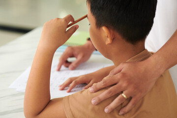 Father patting son on shoulder to support him when he is doing homework