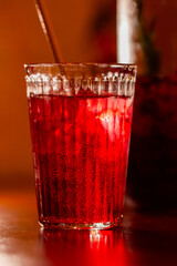 fruit lemonade in a glass with ice, bright red refreshing cold drink