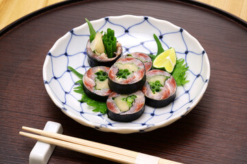 A Japanese sushi restaurant roll dish of pickled sardines and ginger wrapped in nori seaweed.