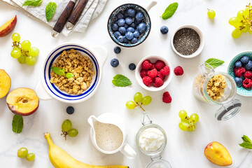 Different ingredients for cooking a healthy breakfast setup with granola, assorted fresh fruits,...