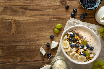 Healthy breakfast bowl topped with fresh fruits, yogurt, granola, chia seeds and coconut on a...