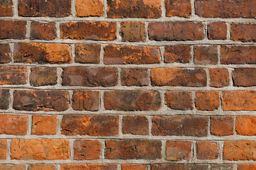Fototapeta premium Wall of old red clay bricks. Ruined vintage stone background. Rough aged masonry backdrop. Surface of grunge brick texture for design and decoration. Loft style for exterior and interior decoration