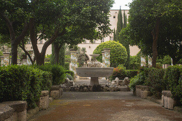 Pathway through a park with fountain and beautiful tiled pillars plated at the cloister garden of Santa Chiara Monastery, Naples, Italy. Vacation in Italy