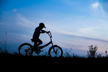 Obraz premium A Happy child and bike concept in park outdoors silhouette
