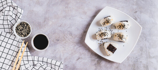 Homemade onigiri rice balls with tuna and nori on a plate on the table top view web banner
