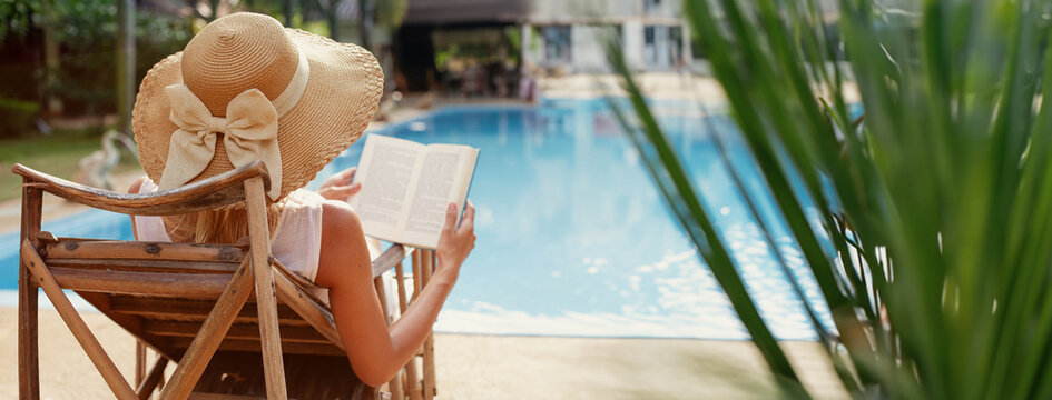 summer holidays, woman reading book near swimming pool in hotel, vacations, female tourist wearing beach hat, banner background with copyspace