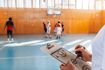 Cropped shot of a elderly male coach drawing game tactics on a coach clipboard